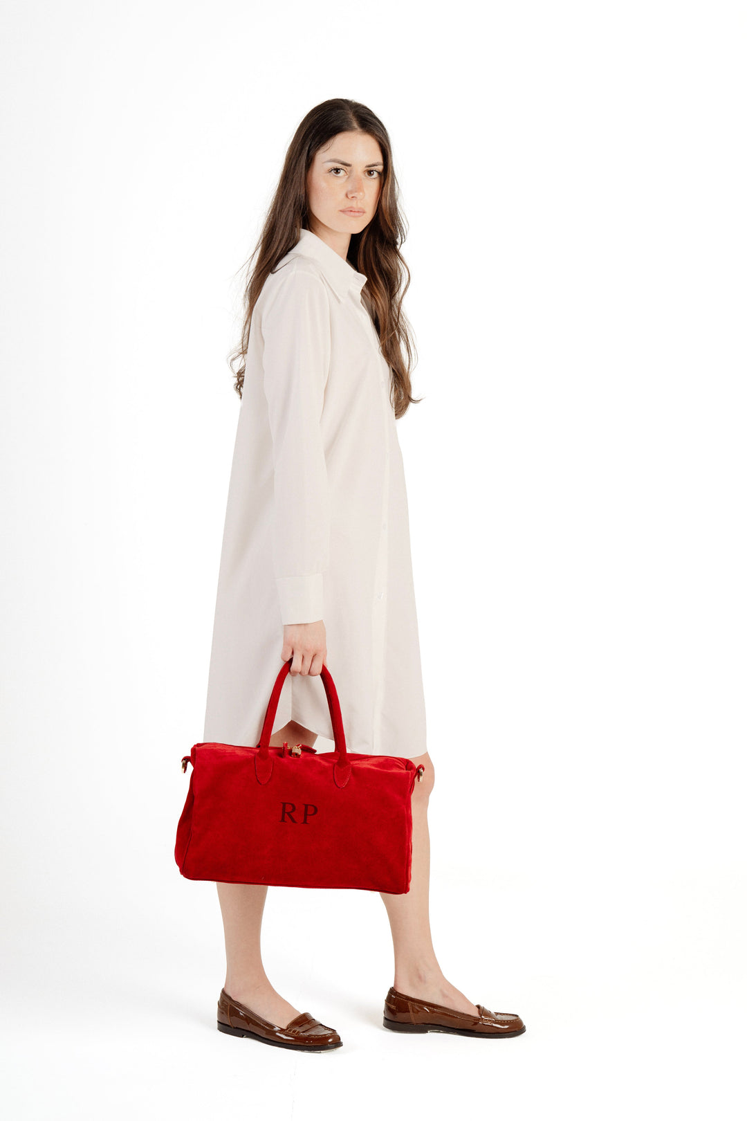 Woman in white dress holding red handbag against white background