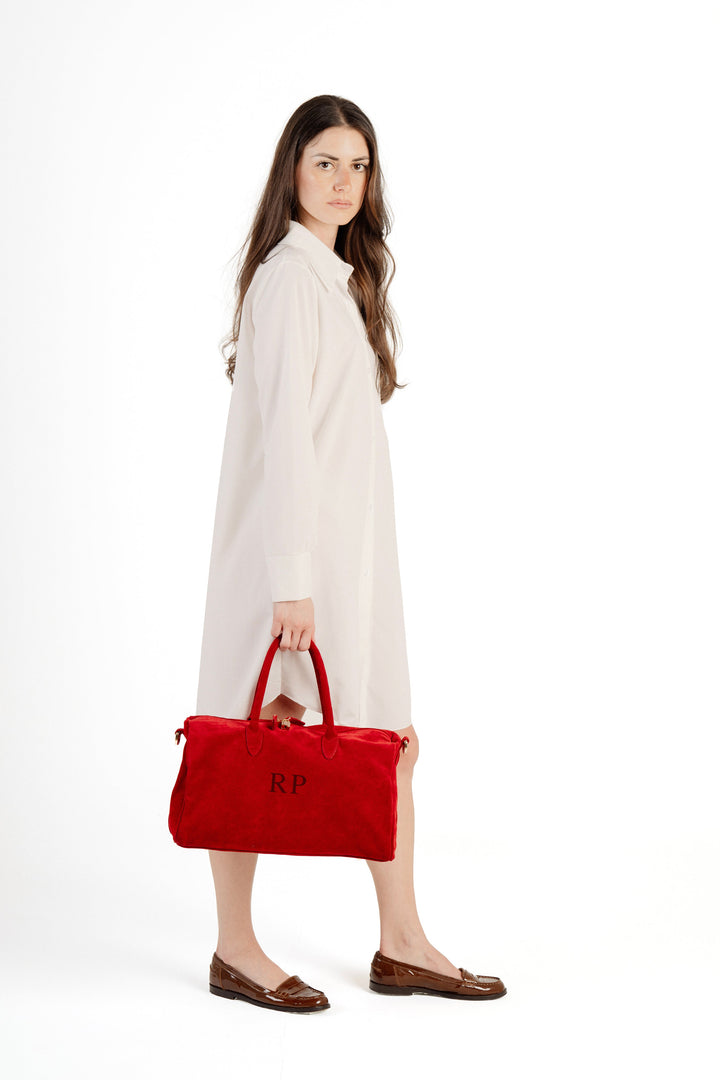 Elegant woman in white dress holding a red handbag