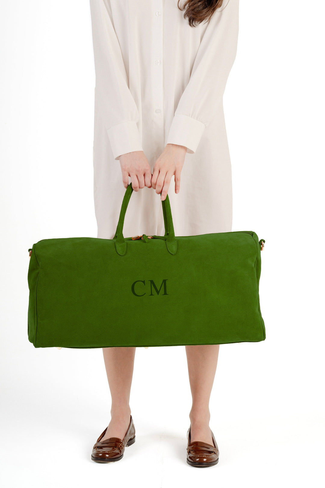 Woman holding large green monogrammed travel bag