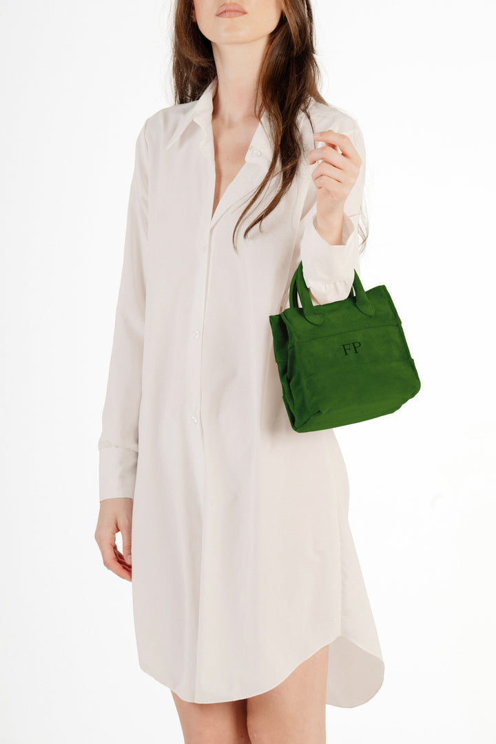 Woman wearing white dress holding small green handbag