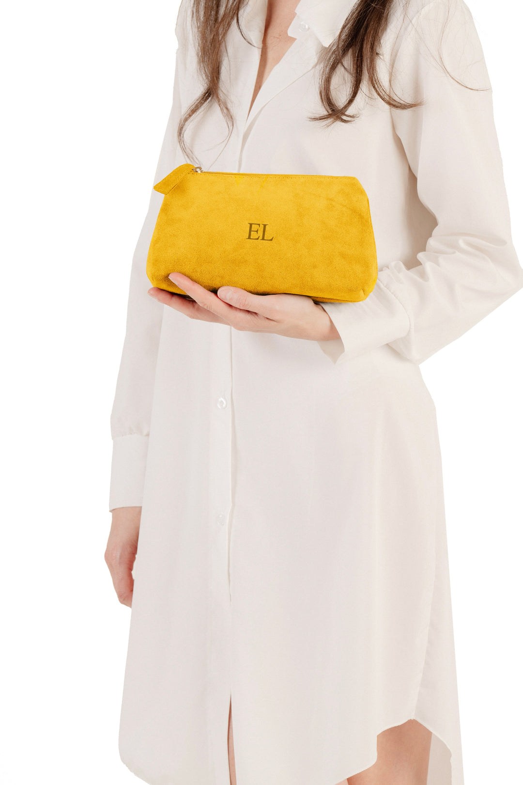 Woman in a white dress holding a yellow clutch bag against a white background