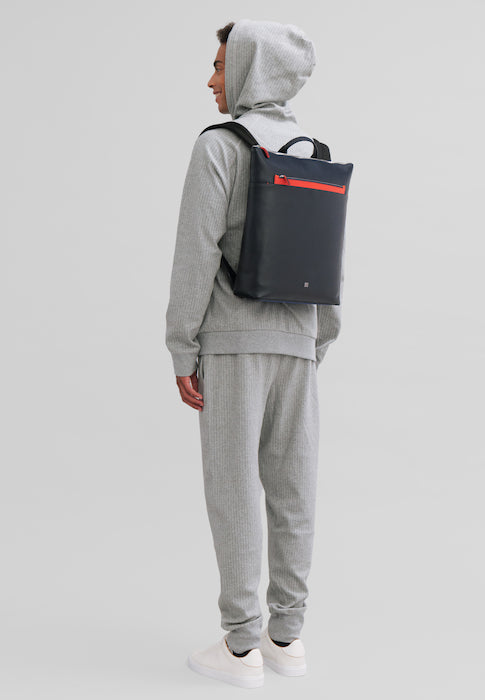 Person in a gray hoodie and sweatpants wearing a black and red backpack