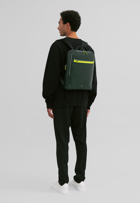 Young man in black clothing wearing a stylish green backpack with yellow accents