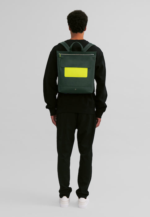 Man wearing a black outfit with a dark green and yellow backpack, viewed from the back