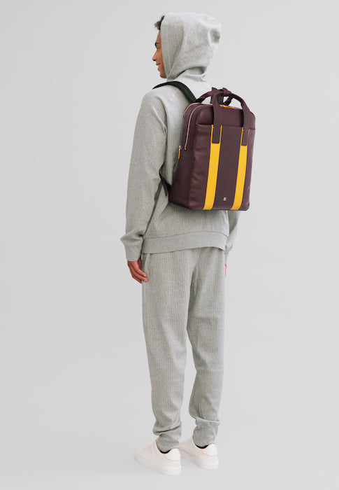 Person in grey tracksuit wearing a stylish brown and yellow backpack