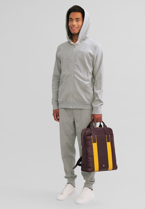 Man in a gray tracksuit holding a stylish purple and yellow bag