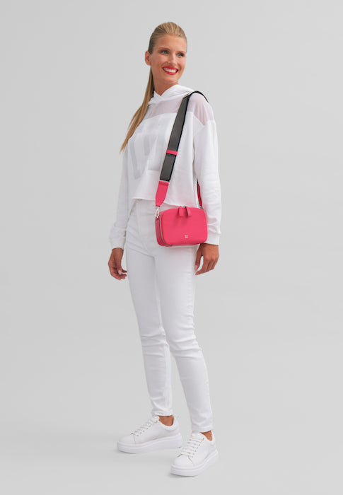 Woman wearing white outfit with pink handbag standing on white background