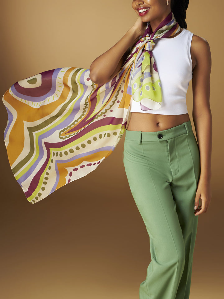 Woman wearing a colorful silk scarf with a white tank top and green pants