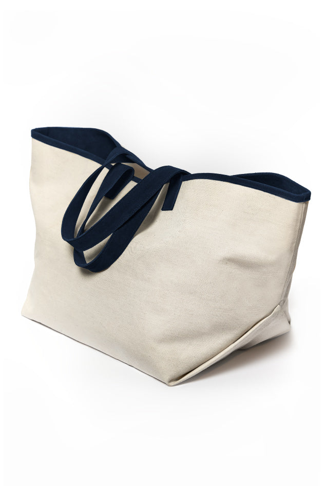 Large beige canvas tote bag with dark blue handles on a white background