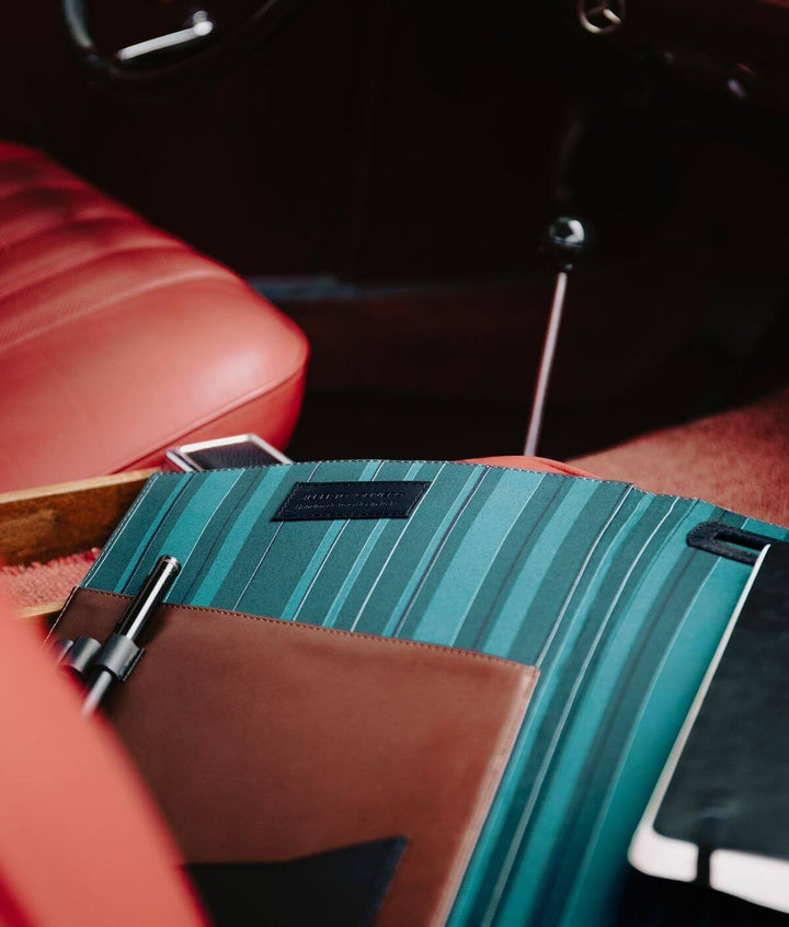 Close-up of vintage car interior with red leather seats and teal striped folder