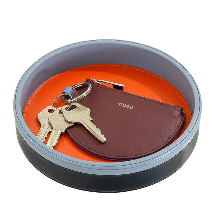 Round tray with orange interior holding keys and a small maroon pouch