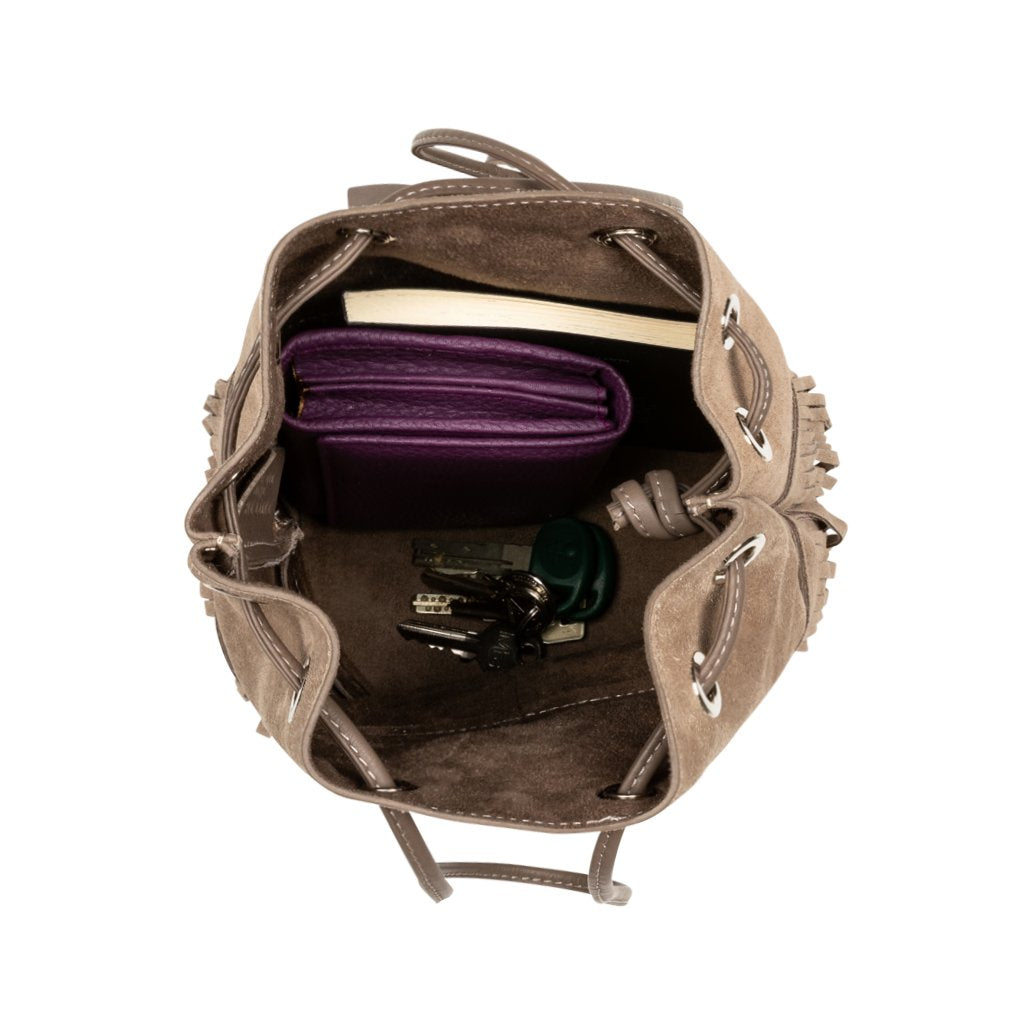 Top view of an open handbag containing a purple planner, keys, and other personal items on a white background