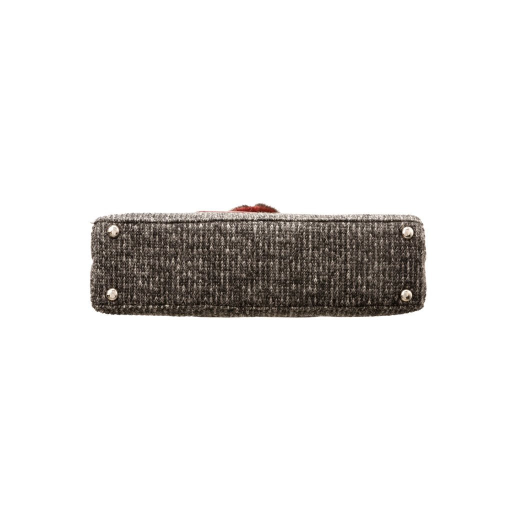 Bottom view of a rectangular gray woven handbag with metal studs