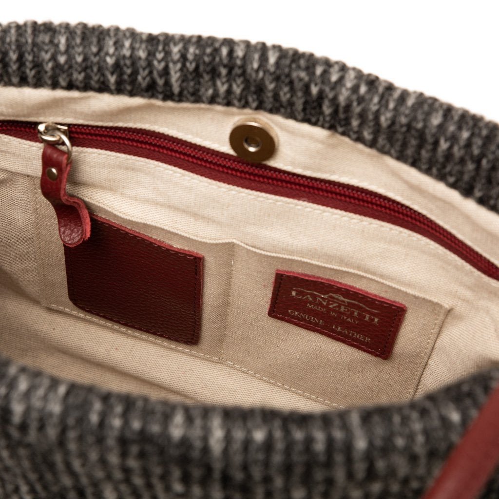 Interior of a gray knitted handbag with beige lining and multiple pockets