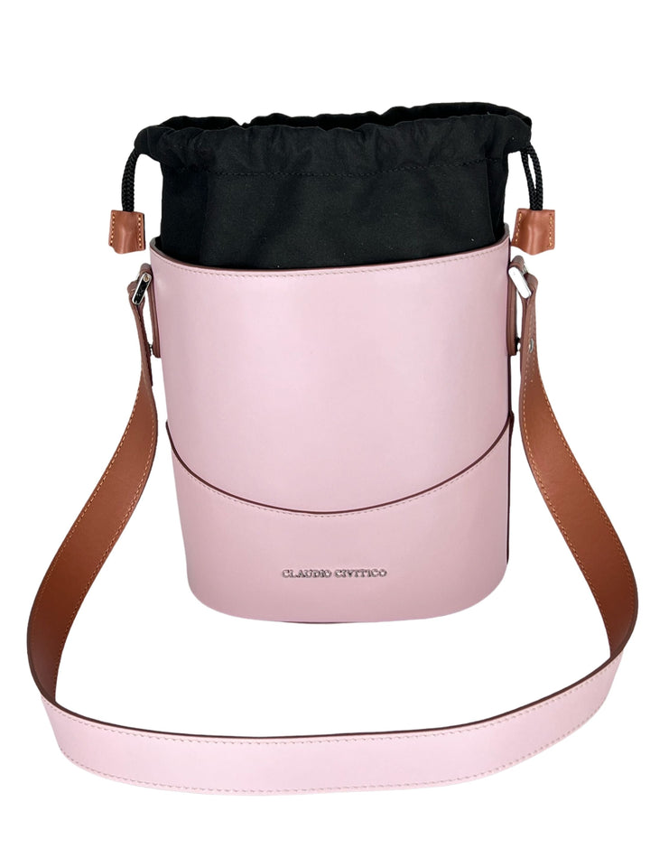 Pink bucket bag with brown leather strap and black drawstring closure