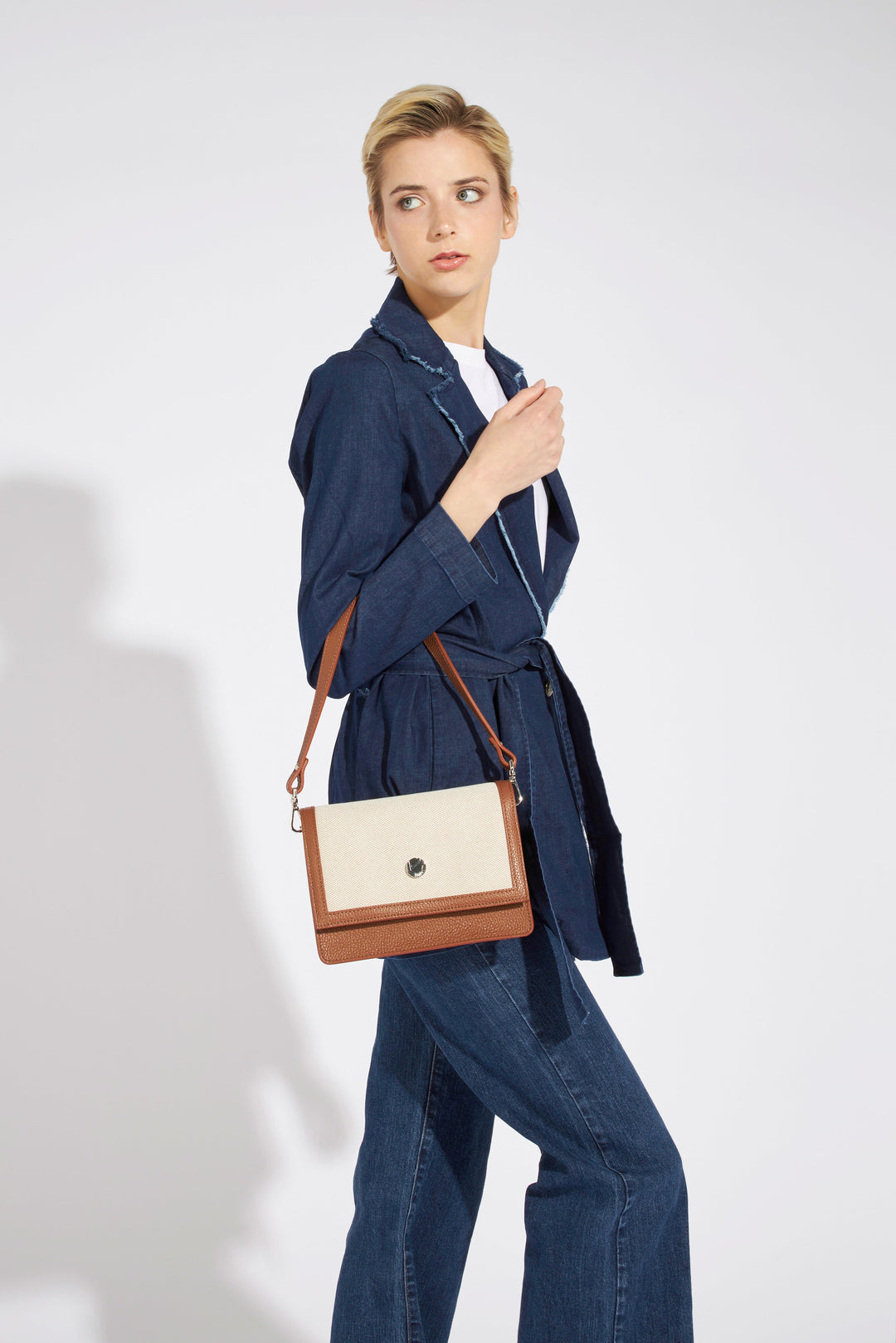 Woman wearing a stylish blue denim jacket and jeans with a white purse on shoulder