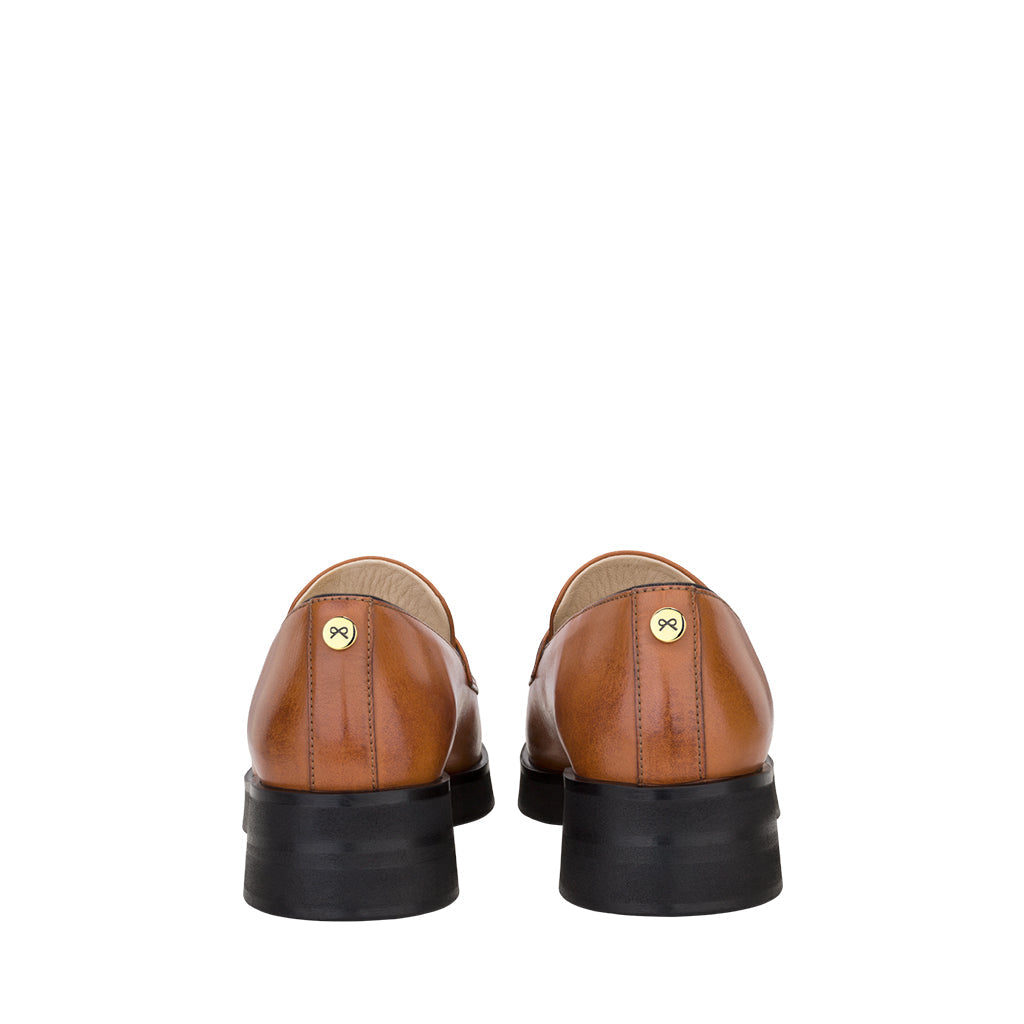 Rear view of brown leather dress shoes with black soles on a white background