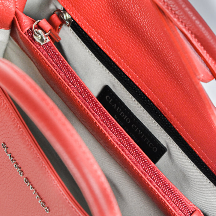 Close-up of an open red leather handbag with metal zipper and Claudio Citricco label inside