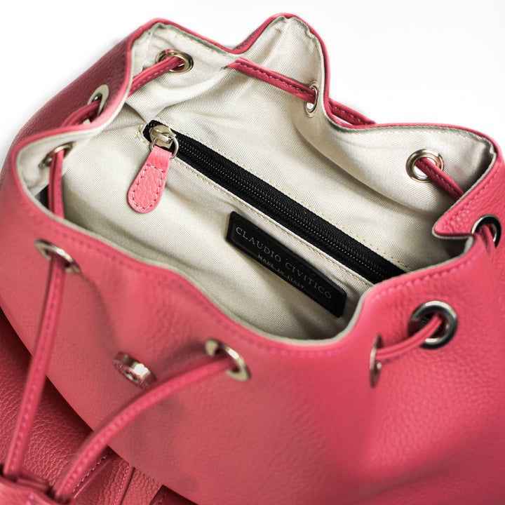 Open pink leather handbag with drawstring closure showing interior pockets and brand label