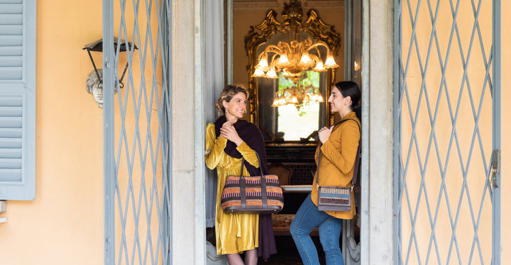 Two women with stylish handbags standing in a doorway of an elegant building