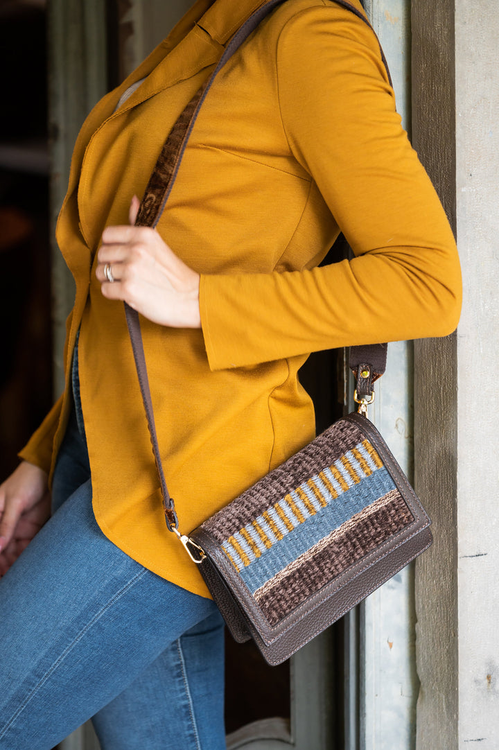 Woman wearing mustard jacket and jeans holding a stylish woven handbag