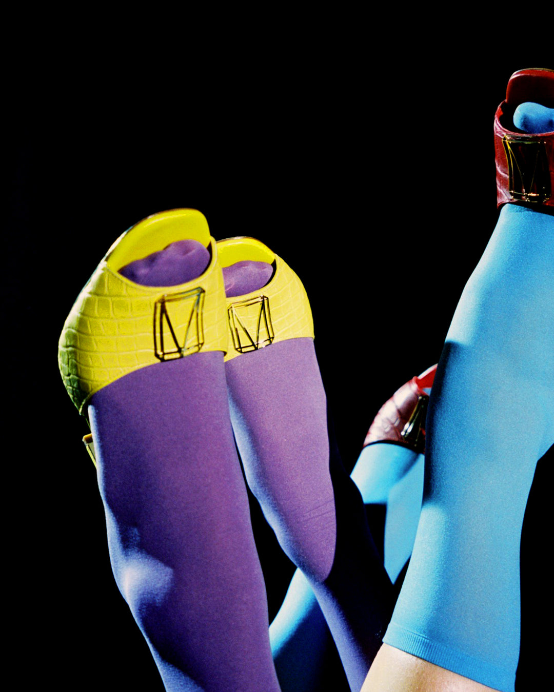 Colorful high-heeled shoes paired with vibrant socks against a black background