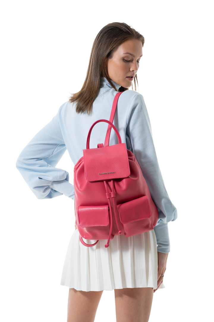 Woman wearing a blue blouse and white skirt with a pink leather backpack