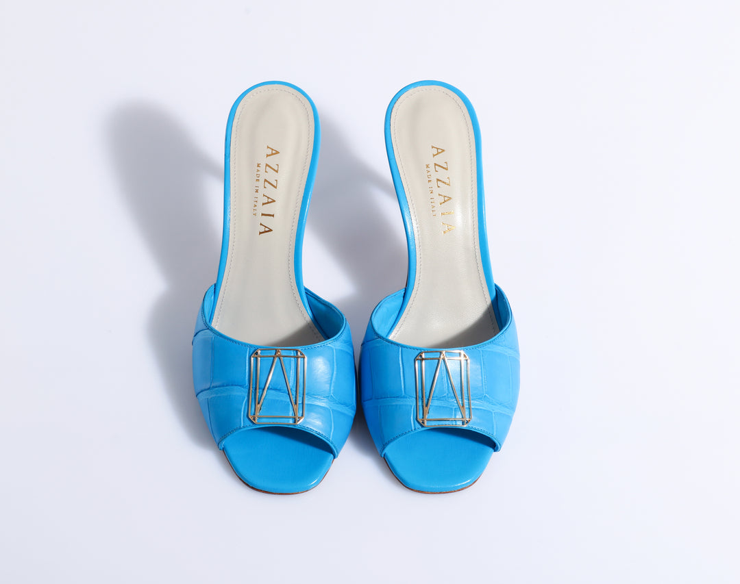Blue AzzaiA slide sandals with gold buckle detail, top view