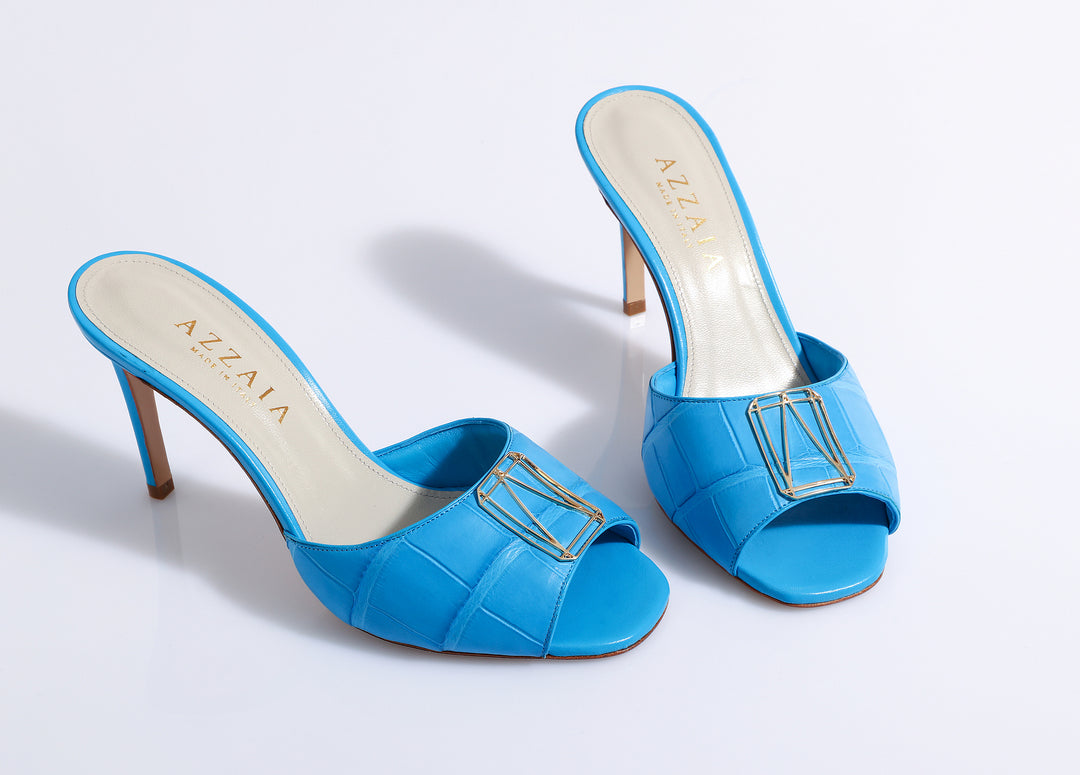 Bright blue high-heeled sandals with open toe design and gold metal accent