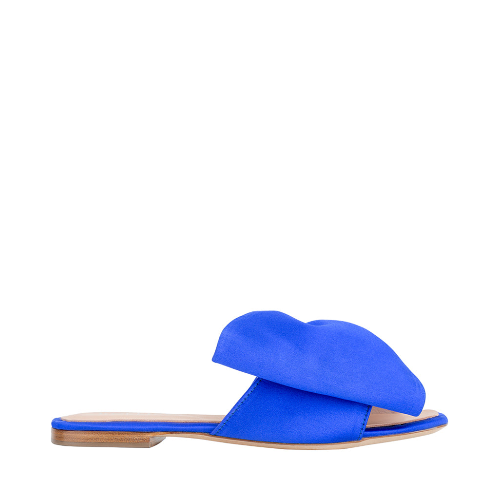 Bright blue open-toe flat sandal with a large bow detail on the strap