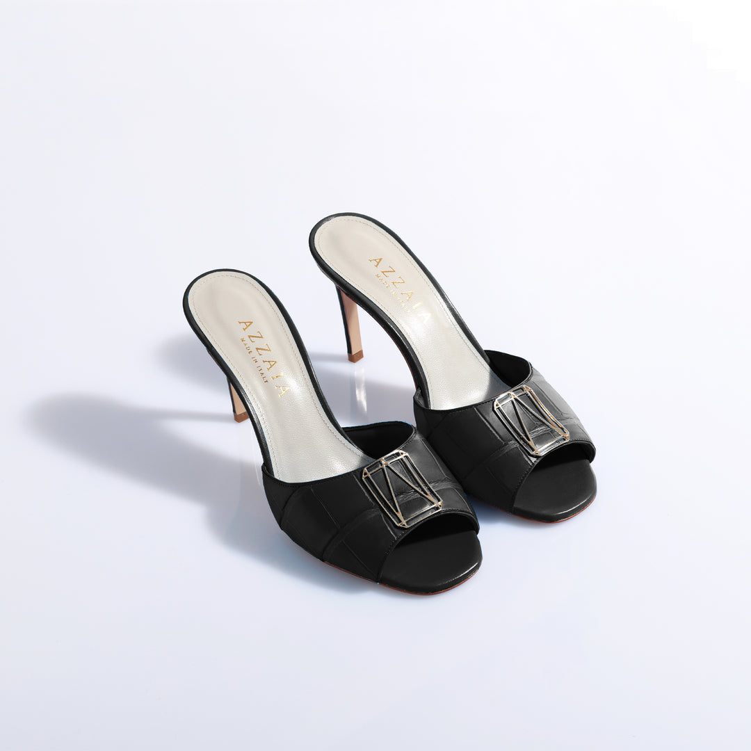 Black high heel mules with buckle detail on white background