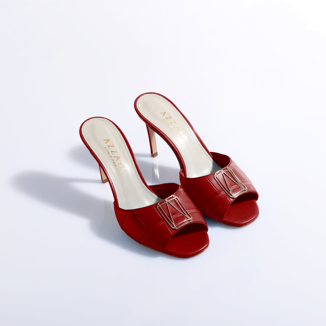 Red high heel mules with buckle detail on white background