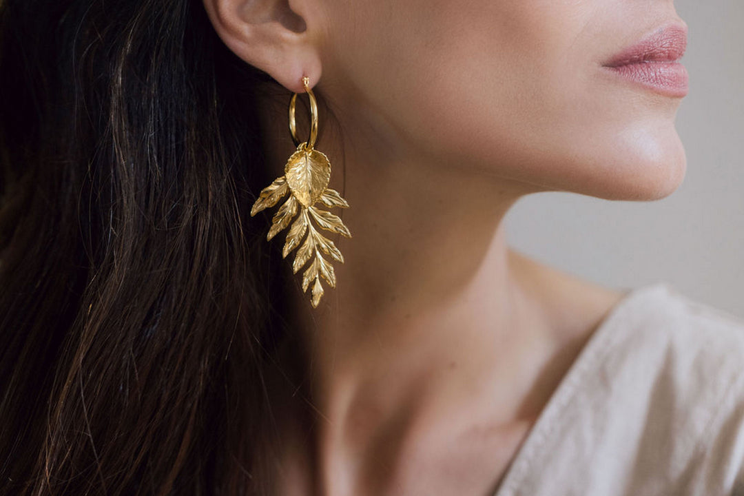 Close-up of woman wearing gold leaf earrings