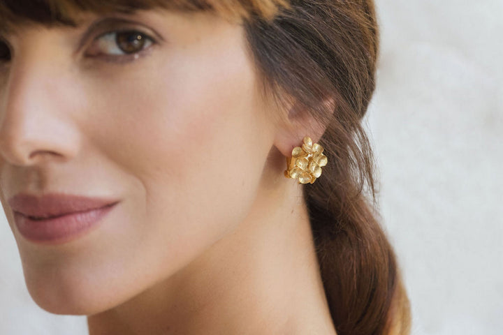 Woman wearing elegant gold floral earrings close-up