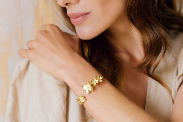 woman wearing gold flower bracelet on wrist