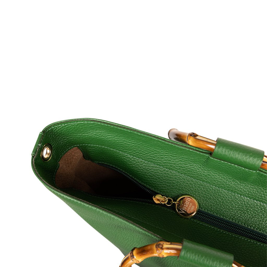 Top view of an open green leather handbag with gold zipper and bamboo handles