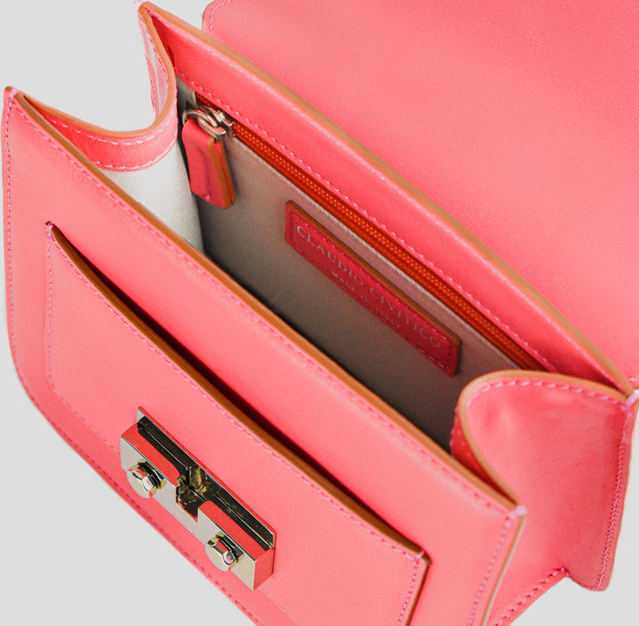 Top view of an open pink leather handbag with a metallic clasp and interior pocket